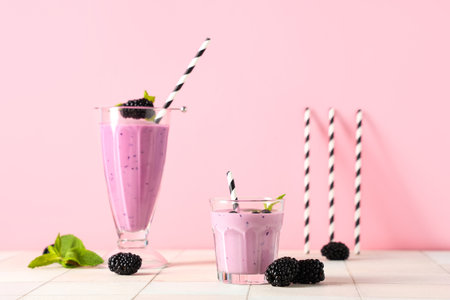 Glasses of fresh smoothie with blackberries and mint on white tile tableの写真素材