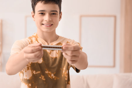 Teenage boy with harmonica at home, closeup