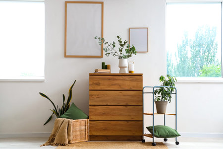 Interior of living room with green plants, commode and blank frames