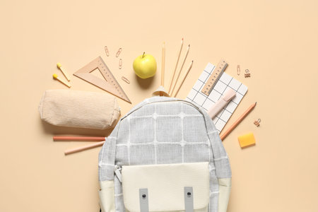 Tasty apple, backpack and different school stationery on beige background