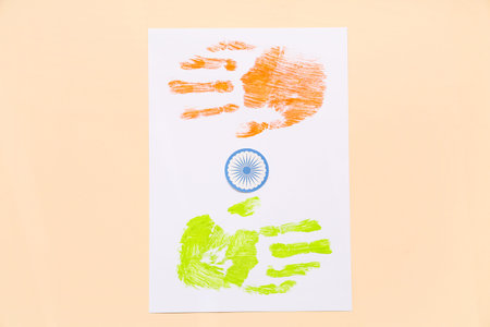 Paper sheet with palm prints in colors of Indian flag on beige background. Indian Independence Day