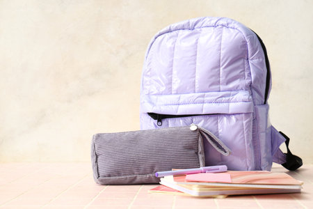 Lilac backpack with school supplies on table against white grunge wallの写真素材