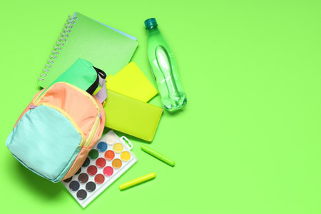 Backpack with school supplies and bottle of water on green background. Top viewの写真素材
