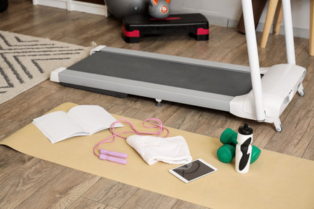Tablet computer with sports equipment and treadmill in room
