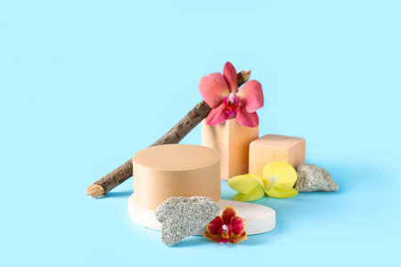 Decorative podiums with beautiful orchid flowers and tree branch on blue backgroundの写真素材