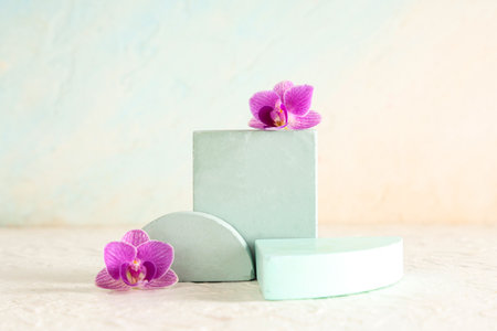 Decorative podiums with beautiful purple orchid flowers on light blue backgroundの写真素材