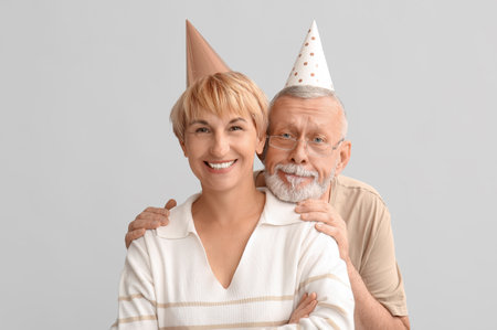 Mature couple in party hats on light backgroundの写真素材