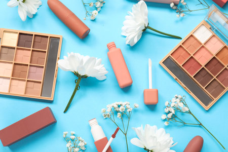 Beautiful composition with flowers and decorative cosmetics on blue background, closeupの写真素材