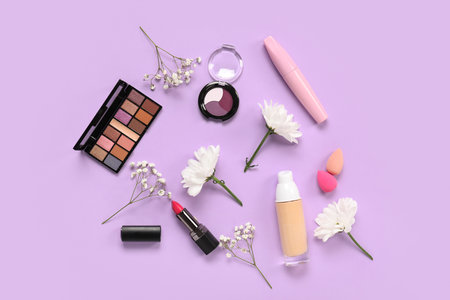 Beautiful composition with flowers, brushes and decorative cosmetics on lilac backgroundの写真素材