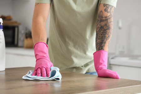 Young man cleaning table in kitchenの写真素材