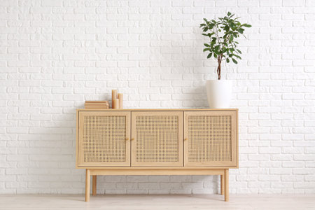 Houseplant on wooden cabinet near white brick wall in roomの写真素材