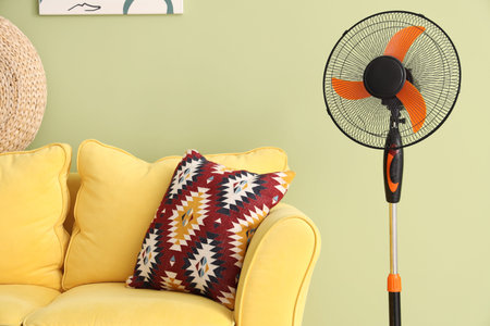Modern electric fan and yellow sofa near green wall