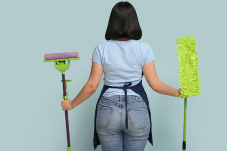 Young woman with floor mops on blue background, back viewの写真素材
