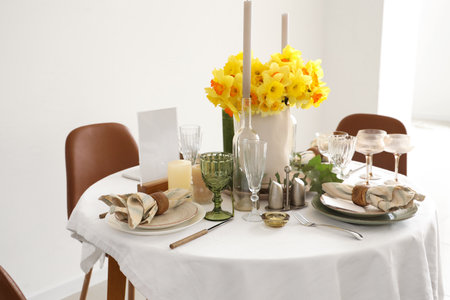 Beautiful table setting with daffodils and candles for wedding celebration in roomの写真素材