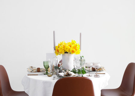 Beautiful table setting with daffodils and candles for wedding celebration in roomの写真素材