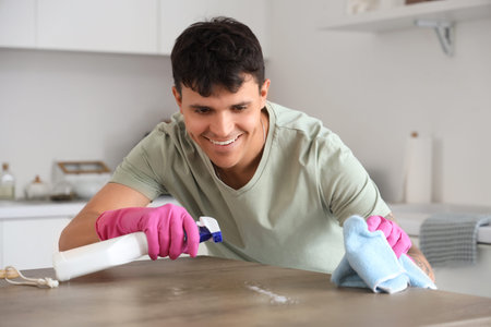 Young man cleaning table in kitchen