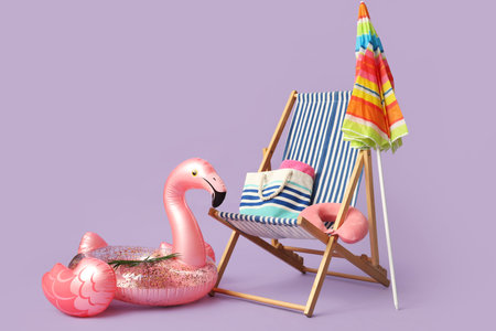 Striped deck chair with colorful umbrella and inflatable ring on lilac background
