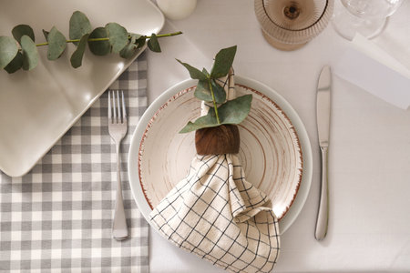 Beautiful table setting with eucalyptus branches for wedding celebration in room, closeup