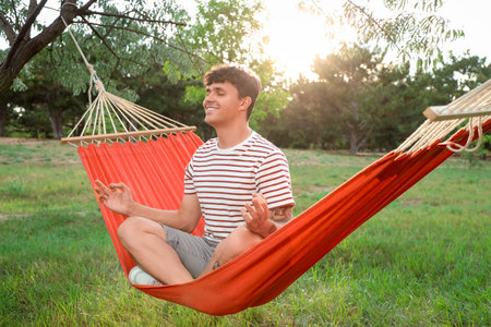 Young man meditating in hammock outdoors