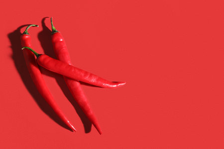 Spicy chili peppers on red backgroundの写真素材