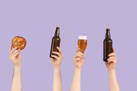 Hands with beer and pretzel on lilac backgroundの写真素材