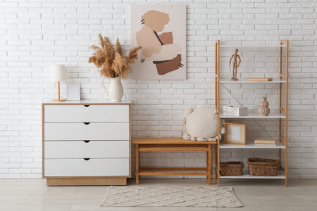 Vase with dry reeds on dresser near white brick wall in living roomの写真素材