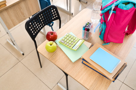 Apples with school stationery on desk in classroom, top viewの写真素材
