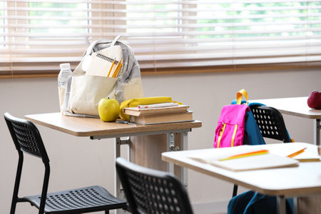 Apple with books, pencil case and backpack on desk in classroomの写真素材