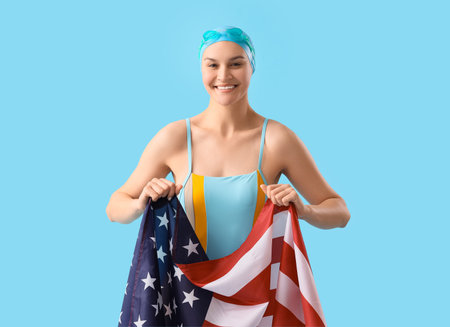 Professional young female swimmer with flag of USA on blue backgroundの写真素材