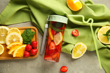 Sports bottle of fresh infused water with strawberries, orange and lemon on gray backgroundの写真素材