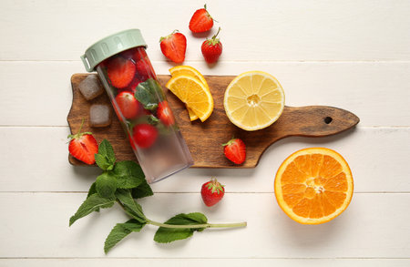 Sports bottle of infused water with strawberries, lemon and mint on white wooden backgroundの写真素材