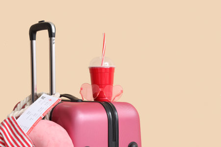 Packed suitcase with drink and tickets in beach bag near beige wallの写真素材