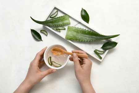 Female hands with bowl of aloe vera gel and spoon on white backgroundの写真素材