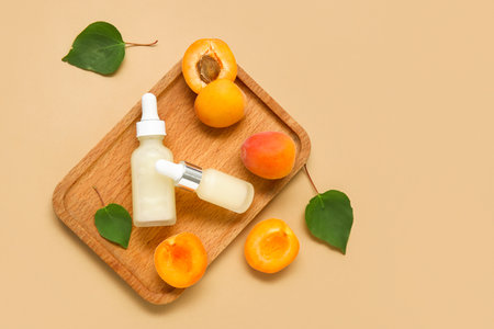 Bottles of cosmetic oil with fresh apricots on brown backgroundの写真素材