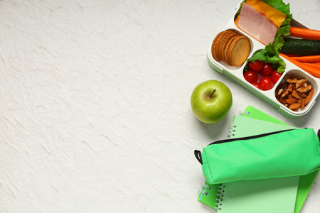 Lunch box with sandwich, green apple and school supplies on white background. Top viewの写真素材
