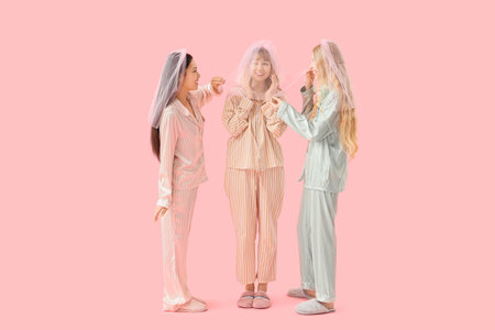 Young woman and her bridesmaids in pajamas on pink background. Hen Partyの写真素材