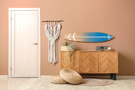 Chest of drawers, houseplant and surf board on beige wall in stylish roomの写真素材