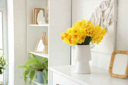 Vase with daffodils on commode in living roomの写真素材