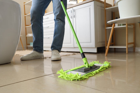 Young man mopping floor in bathroom, closeupの写真素材