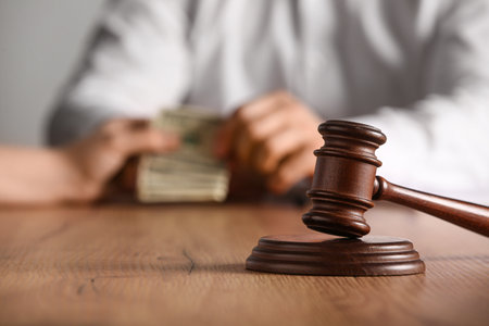 Judge gavel on table against male lawyer taking bribe in officeの写真素材