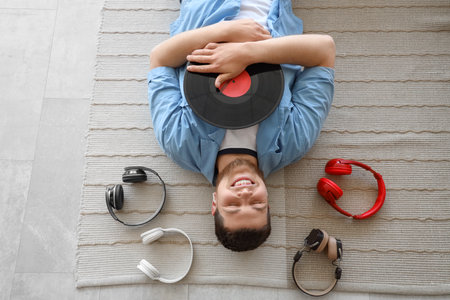 Young bearded man with vinyl disk and headphones lying on the floor, top viewの写真素材