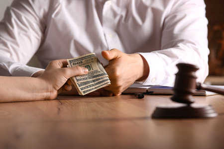 Male judge taking bribe at table in officeの写真素材