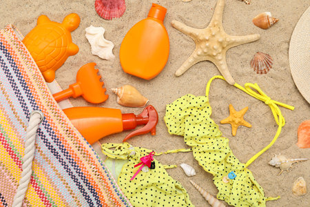 Beautiful composition with sunscreen, swimsuit and beach accessories for children on sand