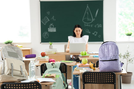 Desks with apples and school stationery in classroom, closeupの写真素材