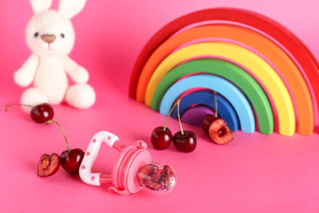 Baby nibbler with sweet cherry and toys on color backgroundの写真素材