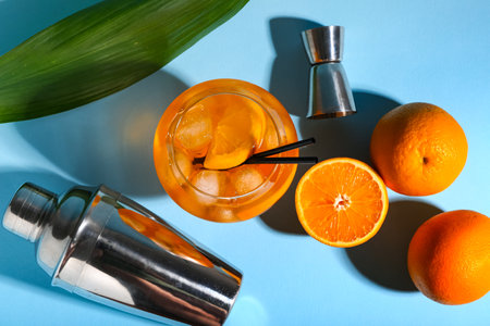 Glass of spritz cocktail with oranges and shaker on blue backgroundの写真素材