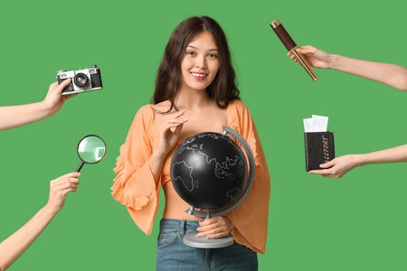 Young Asian woman with globe and hands with items on green background. Travel conceptの写真素材