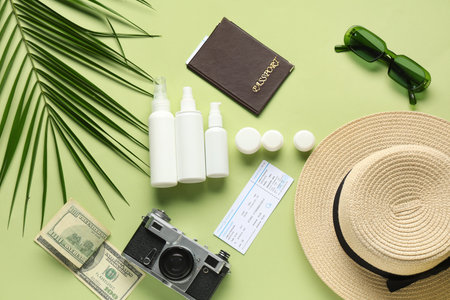 Composition with cosmetic travel kit, female beach accessories, ticket and palm leaf on green...