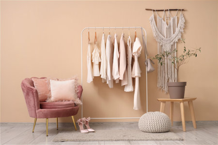 Rack with white clothes near beige wall in roomの写真素材