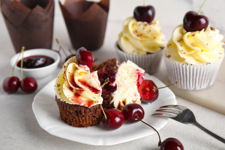 Plate and board with sweet cherry cupcakes on white backgroundの写真素材